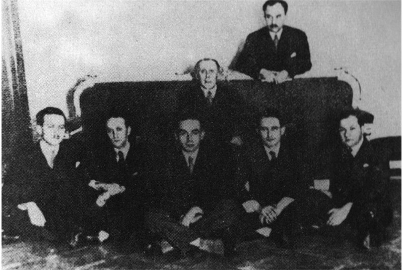 Fig. 4
Adolf Loos fra i suoi allievi in occasione
del suo sessantesimo
compleanno, de Finetti &egrave; in piedi
dietro al divano. (&laquo;Parametro&raquo;, n.
126, maggio 1984, p. 13).